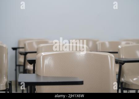 Leerer Unterricht an der Universität oder Schule mit Stühlen und Beistelltisch und großem Brett im Hintergrund. Die Stühle sind in Reihen angeordnet. Stockfoto