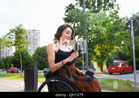 Junge Frau im Rollstuhl mit einem Smartphone Stockfoto