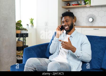 Headshot des lächelnden, multirassischen Geschäftsmannes in elegantem Casual-Hemd, der auf dem Smartphone spricht und die Kamera anschaut. Mann, der ein angenehmes Telefongespräch geführt hat Stockfoto
