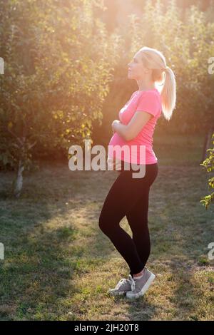 Eine Schwangerin genießt den Sonnenaufgang im Garten Stockfoto