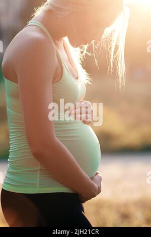 Profil einer Schwangeren, die ihren Bauch umarmt Stockfoto