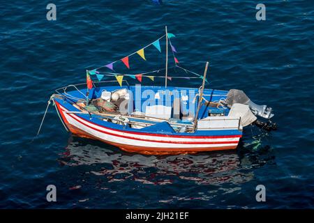 Boot mit bunten Fahnen im blauen Meer in Camara dos Lobos, Madeira, Portugal Stockfoto