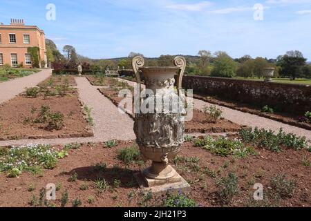 Eine gut verwitterte griechische Urne in den neu gepflanzten Blumenbeeten eines englischen Herrenhauses Stockfoto