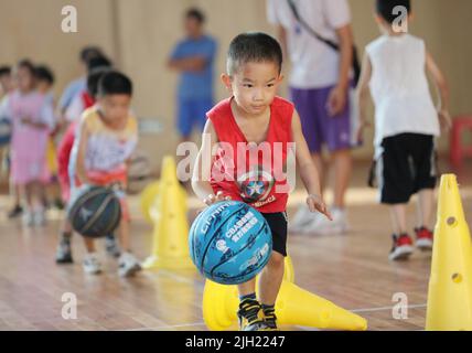 Yongzhou, Chinas Provinz Hunan. 14.. Juli 2022. Kinder tröpfeln die Kugeln während eines Basketballtrainings in Yongzhou, der zentralchinesischen Provinz Hunan, 14. Juli 2022. Kredit: He Hongfu/Xinhua/Alamy Live Nachrichten Stockfoto