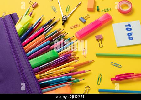 Stellen Sie sich verschiedene Büromaterialien und Plastikutensilien, Notizbücher, Buntstifte auf gelbem Hintergrund vor Stockfoto