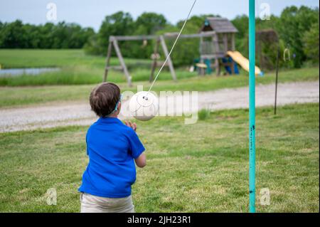 Tetherball wird in einem Spiel mit einem kleinen Jungen getroffen und umgeseilt. Stockfoto