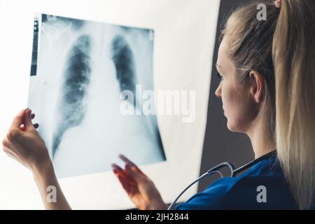 Nahaufnahme einer nicht erkennbaren jungen kaukasischen Ärztin, die eine Röntgenaufnahme der Lunge hielt und die Ergebnisse ihrer Patientin untersuchte. Medizinisches Fachpersonal. Hochwertige Fotos Stockfoto