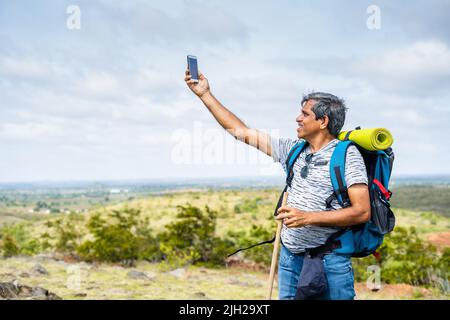 Reisende, die beim Wandern den Empfang des Mobilfunknetzes oder die Verbindung auf dem Hügel überprüfen - ohne auf drahtlose Technologie, Internet und Kommunikation zu achten Stockfoto