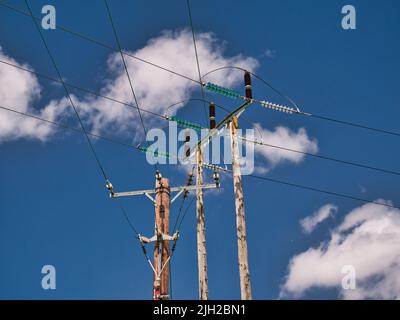 Zwei Strommasten, die Strom über das britische Stromnetz liefern, zeigen Stromkabel, Isolatoren und andere Geräte. An einem sonnigen Tag aufgenommen Stockfoto