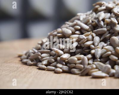 Ein Haufen geschälter Sonnenblumenkerne auf einer hölzernen Oberfläche, Makroaufnahme. Samen ohne Schale. Stockfoto