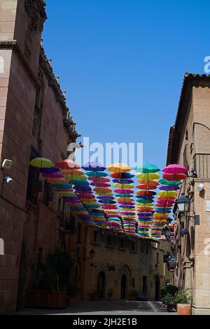 Bunte Regenschirme hängen über einer malerischen Straße in der Stadt Stockfoto