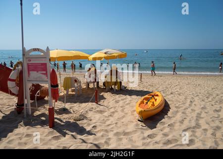 Strandschwimmer beobachten das Meer mit einem Kajak in der Nähe, und Leguard-Ausrüstung, um Leben im Meer zu retten. Menschen, die am Strand mit Rettungsschwimmern in der Nähe spazieren gehen. Stockfoto