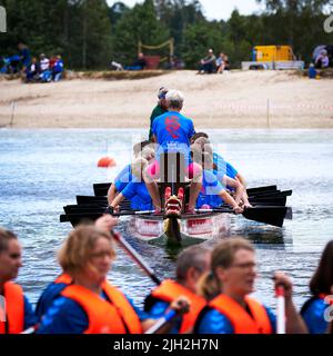 Gifhorn, 10. Juli 2022: Frontansicht eines sich bewegenden Drachenbootes, in dem Ruderer mit blauen Hemden gekleidet sind Stockfoto