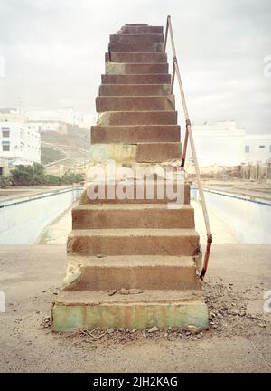 Schritte zu einem verfallenden Steintauchbrett. Öffentlicher Pool mit Whirlpool. Sidi Ifni , Südwestküste Marokkos. Nordafrika. Stockfoto