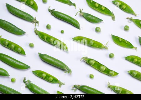 Rotierende junge grüne Erbsen auf weißem Hintergrund, gesundes Lebensmittelkonzept, trendiger Gemüsehintergrund. Stockfoto