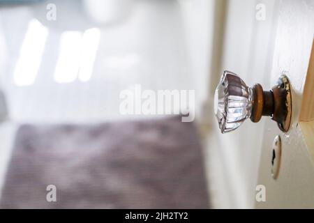 Ein antikes Vintage Glas Türknauf zu einem schmalen Badezimmer in einem kleinen Häuschen. Stockfoto