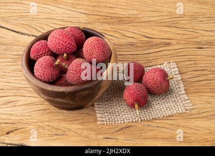 Litschi in einer Schüssel über einem Holztisch. Stockfoto