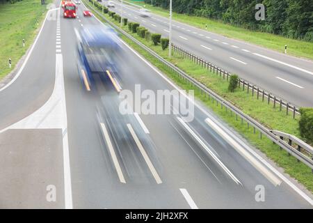 Interstate Highway Transport im Sommer Tag. Bewegungsunschärfen von Lastwagen und Autos, die auf einer Autobahn vorbeifahren. Transport- und Reisekonzept Stockfoto