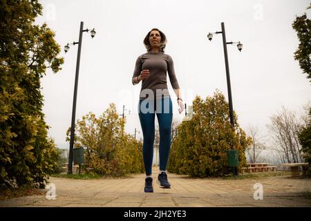 Frau mittleren Alters springt und rennt auf die Treppe Stockfoto