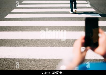 Fußgänger Zebra Nahaufnahme, Smartphone im Vordergrund Stockfoto