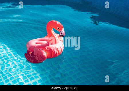 Flamingo Tropical. Rosa aufblasbare Flamingo auf dem Hintergrund des Wassers des Sommerpools, Strand. Poolparty Sommerurlaub. Stockfoto