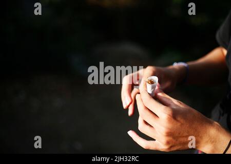 Männliche Hände, die eine Tabakzigarette aufrollen Stockfoto