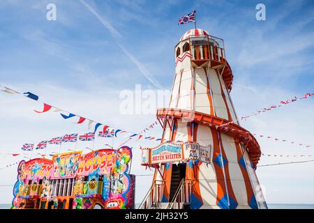 Buntes Helter-Skelett auf dem Messegelände in Hunstanton, umgeben von Union Jack-Ampfen, das im Juli 2022 in Norfolk abgebildet wurde. Stockfoto