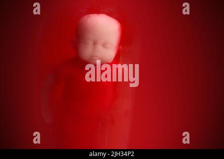 Babypuppe im roten Blut sieht aus wie eine Abtreibung. Stockfoto