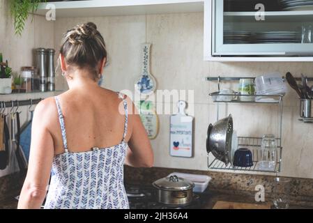 Junge Frau von hinten, die in der Küche Essen zubereitet. Stockfoto