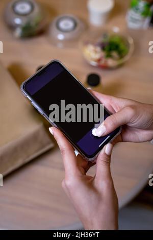 Ein schwarzes Smartphone in weiblichen Händen. Telefonvorlage. Stockfoto