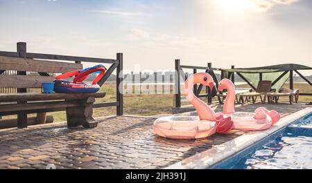 Zwei aufblasbare Flamingos in der Nähe des Pools mit klarem Wasser unter der Sommersonne Stockfoto