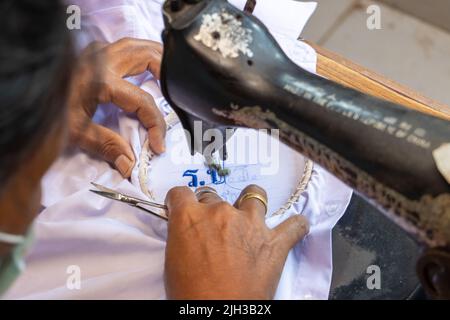 Sticken von Thai-Nummern auf einem Studentenhemd auf einer alten Nähmaschine Stockfoto