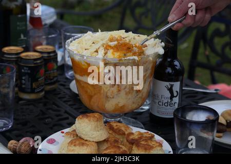 Mann, der die „Platinum Pudding“-Zitrone und Amaretti-Kleinigkeit bei der Street Party serviert, die das Platin-Jubiläum von Queen Elizabeth II in Surrey, England, feiert Stockfoto