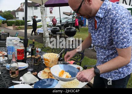 Mann, der die „Platinum Pudding“-Zitrone und Amaretti-Kleinigkeit bei der Street Party serviert, die das Platin-Jubiläum von Queen Elizabeth II in Surrey, England, feiert Stockfoto