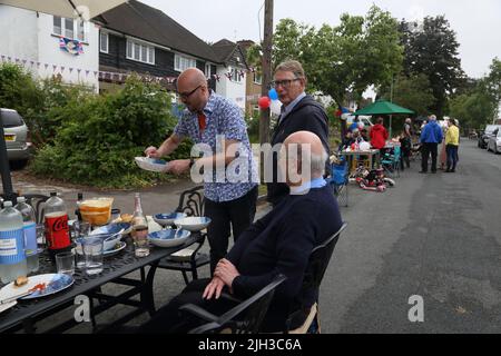 Mann, der die „Platinum Pudding“-Zitrone und Amaretti-Kleinigkeit bei der Street Party serviert, die das Platin-Jubiläum von Queen Elizabeth II in Surrey, England, feiert Stockfoto