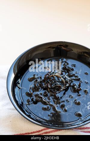 Getrocknete mun-Pilze, traditionelle chinesische Medizin und Küche. Pilze Zutaten in Teller auf beigem Hintergrund Stockfoto