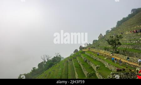 Stöpel zu Fuß auf den Terrassen der atemberaubenden Machu Piccu Stadt, High Angle. Spektakuläre Naturkulisse und historischer Hintergrund mit Kopierraum. Stockfoto