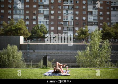 Madrid, Spanien. 14.. Juli 2022. Eine Frau sonnen sich am Stadtstrand von Madrid Rio. Eine zweite Hitzewelle im Sommer betrifft die gesamte iberische Halbinsel, laut der Warnung der Staatlichen Meteorologischen Agentur (AEMET) wird ein Rückgang der Temperaturen am kommenden Montag, den 18. Juli 2022, erwartet. Die Gemeinde Madrid hält den orangefarbenen Wert für Höchstwerte von 40-41 Grad Celsius aufrecht. (Foto von Luis Soto/SOPA Images/Sipa USA) Quelle: SIPA USA/Alamy Live News Stockfoto