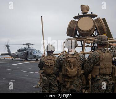 PAZIFISCHER OZEAN (13. Juli 2022) - US-Marine mit Marine Medium Tiltrotor Squadron (VMM) 362 (verstärkt), beobachten einen MH-60s Sea Hawk beim Start, bevor sie an Bord des amphibischen Angriffsschiffs USS Makin Island (LHD 8) die Übung zur Verteidigung der amphibischen Task Force durchführen, 12. Juli. Die Marine Expeditionary Unit 13. wird derzeit an Bord der USS Makin Island gestartet, um Routineoperationen in der US-Flotte von 3. durchzuführen. (USA Marine Corps Foto von Sgt. Kevin G. Rivas) Stockfoto