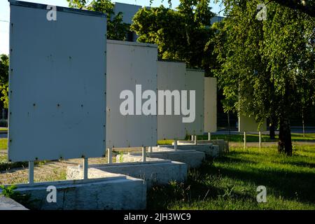 Blank Schild oder Plakat für Werbung auf Bauland, Baugrundstück oder Gewerbefläche auf grüner Wiese mit freier Fläche für Text. Blauer Himmel. Stockfoto