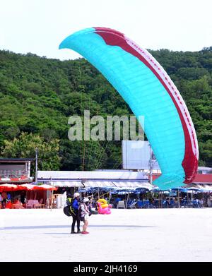 Menschen Paragliding Landung an der Küste am Strand auf der Insel Koh Larn, die Ko Larn oder Ko Laan oder Ko Lan, Thailand, Asien buchstabiert werden kann. Thailand, Asien, Stockfoto