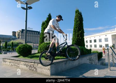 Kiew, Ukraine - 15. Juni 2022: Contract Square. BMX Biker mit Tricks und Stunts Training im Stadtpark. Springen Sie auf bmx Fahrrad in Aktion Stockfoto