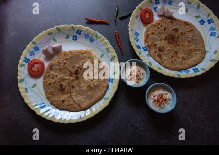 Es wird ein indisches Frühstück mit Aloo Paratha oder gefülltem Fladenbrot mit Kartoffeln serviert. Draufsicht Stockfoto