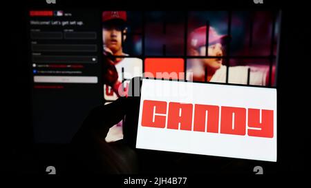 Person, die Mobiltelefon mit dem Logo der US-amerikanischen NFT-Firma Candy Digital auf dem Bildschirm vor der Business-Webseite hält. Konzentrieren Sie sich auf die Telefonanzeige. Stockfoto