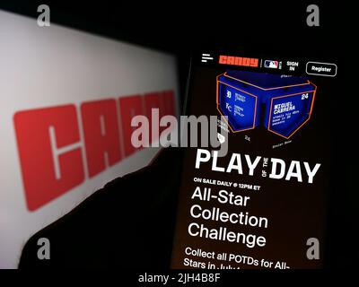 Person, die Mobiltelefon mit der Website der US-amerikanischen NFT-Firma Candy Digital vor dem Unternehmenslogo auf dem Bildschirm hält. Konzentrieren Sie sich auf die Mitte des Telefondisplays. Stockfoto