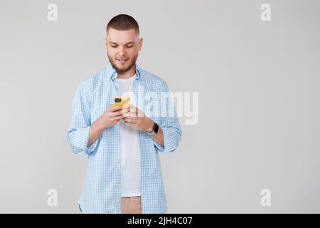 Schöner Mann mit Handy, der im Internet surft Stockfoto