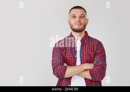 Lächelnder junger Mann, der mit gekreuzten Armen posiert Stockfoto