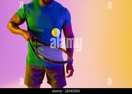 Bild des Mittelteils des afroamerikanischen Tennisspielers in violetter und gelber Neonbeleuchtung Stockfoto