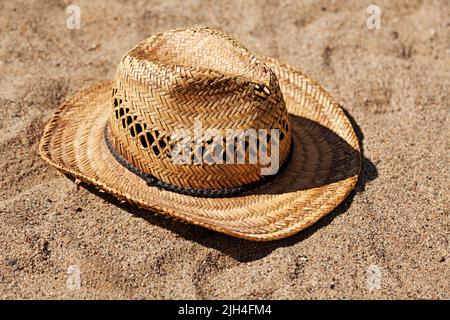 Der Sonnenhut im Cowboy-Stil liegt im Sand Stockfoto