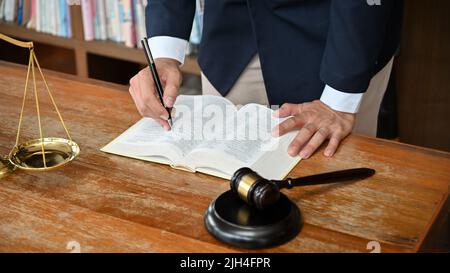 Professioneller und erfolgreicher männlicher Anwalt in formeller Klage, der an seinem Schreibtisch in seinem Büroraum arbeitet. Zugeschnittenes Bild Stockfoto